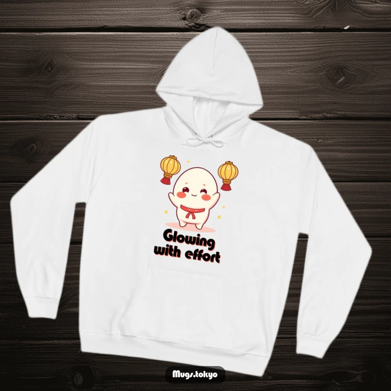Funny hoodie showing a cheerful mochi character with rosy cheeks, attempting to juggle bright lanterns, offering warmth and playful humor.